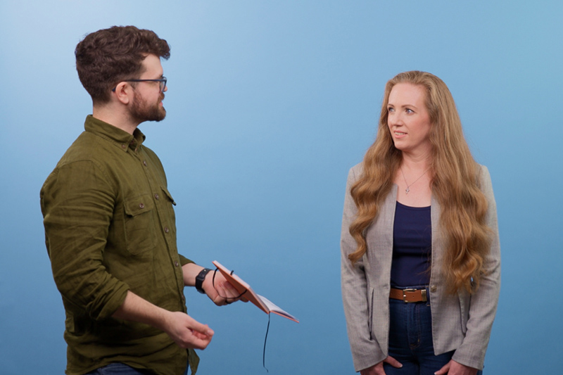 A Vital Studio member talks with a woman in front of a blue backdrop