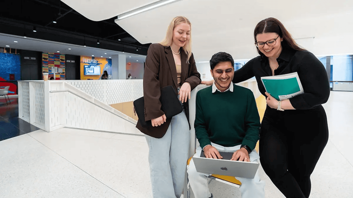 Higher Ed | Paid Search Landing Page Strategy 1 Three professionals smile while reviewing documents together in a modern office lobby.